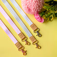 Load image into Gallery viewer, Three fabric straps with leather accents and metal clasps on a yellow background with pink flowers and green leaves.