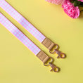 Load image into Gallery viewer, Pink and white checkered strap with beige leather buckle and gold hardware on a yellow background with pink flowers.