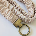 Load image into Gallery viewer, Beige scrunchie with a gold keychain on a white background