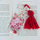 Decorative bookmark with red yarn and 'Smutty Book Lover' design on a book page.