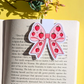 Pink bow-shaped sticker with strawberry pattern on an open book against a yellow background