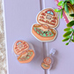 Illustrated earbud cases with scenes inside on a light purple surface.