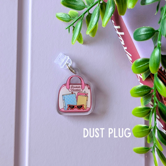 Dust plug with a cute design on a white surface with green leaves.