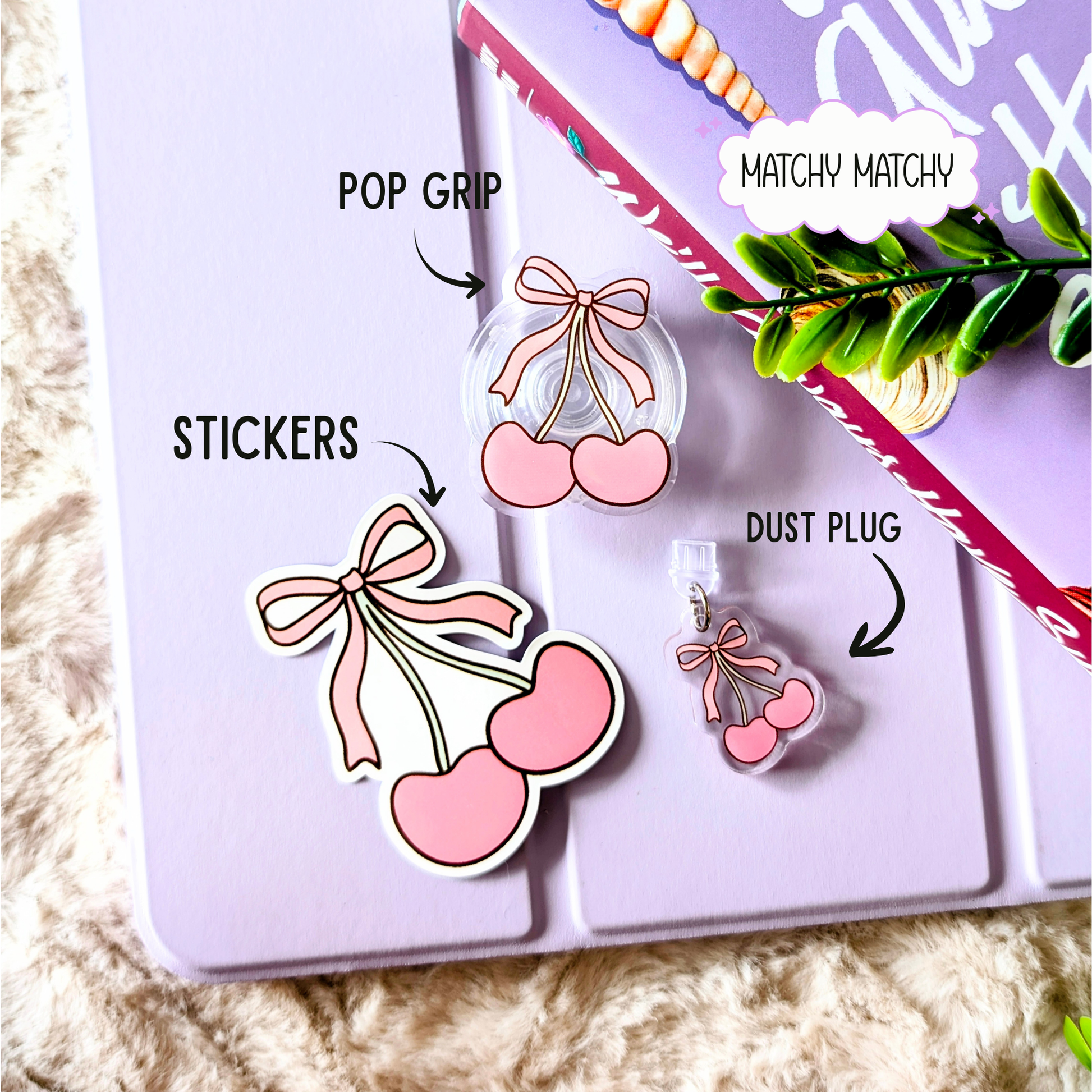Pink cherry and bow-shaped phone accessories on a purple surface with text labels.