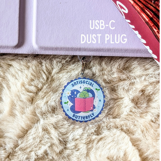 USB-C dust plug with a decorative charm on a fluffy surface