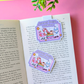 Colorful 'Summer Bookish Weekend' bookmarks on an open book with a pink background