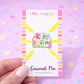 Enamel pin with 'Keep smiling' text on a colorful card against a pink background with polka dots.