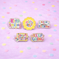 Five colorful enamel pins with motivational phrases on a pink background with confetti.