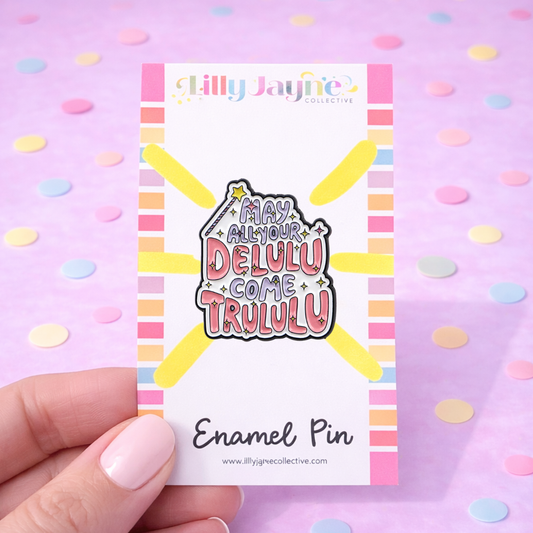 Enamel pin with colorful text on a card held by a hand against a polka dot background