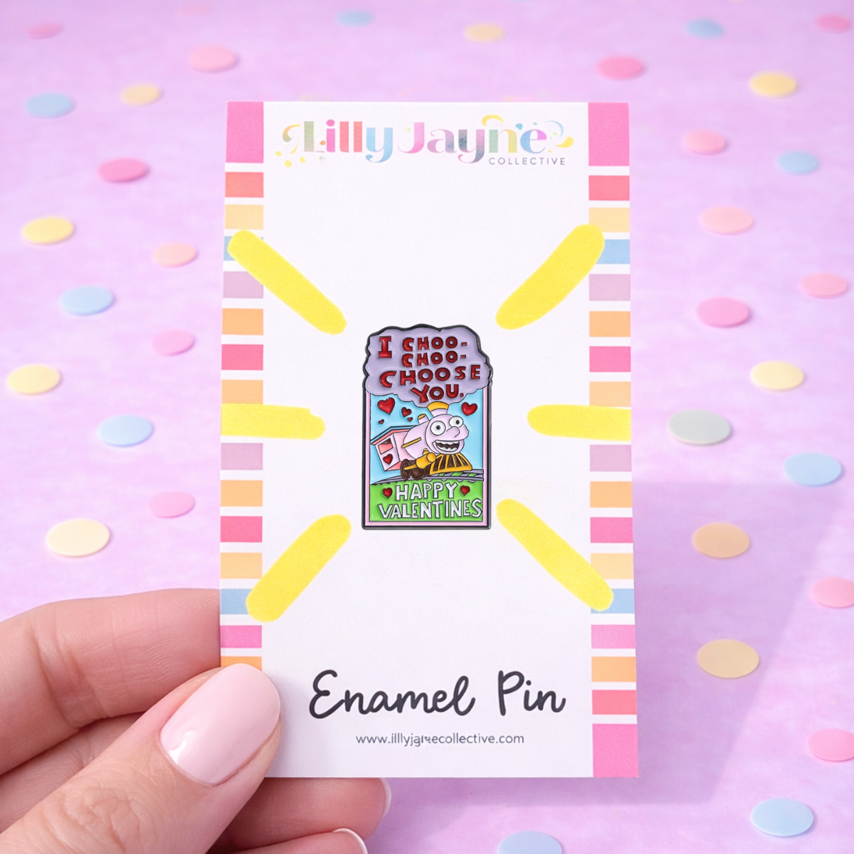Enamel pin on a card held by a hand with a colorful polka dot background