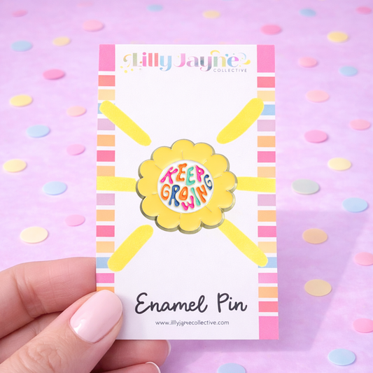 Enamel pin with 'Keep Growing' design on a card held against a polka dot background
