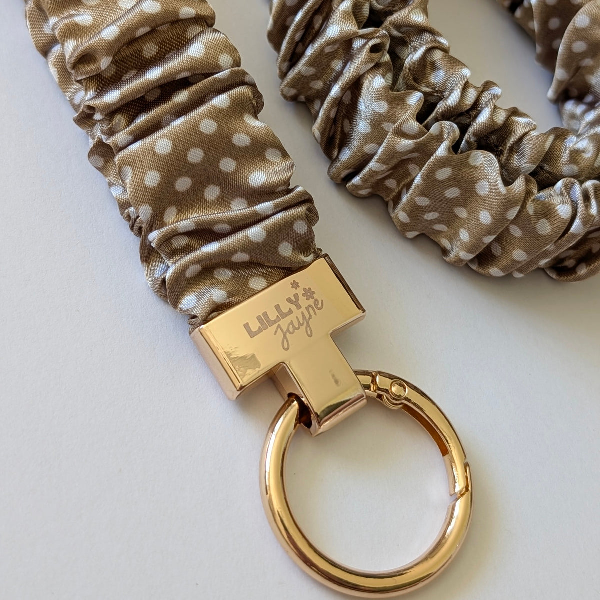 Gold keychain with polka dot scrunchie on a white background