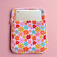 Floral patterned pouch with a phone inside on a pink background