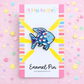 Blue fish enamel pin on a colorful card with 'Lilly Jayne Collective' branding, surrounded by star-shaped decorations.