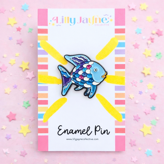 Blue fish enamel pin on a colorful card with 'Lilly Jayne Collective' branding, surrounded by star-shaped decorations.