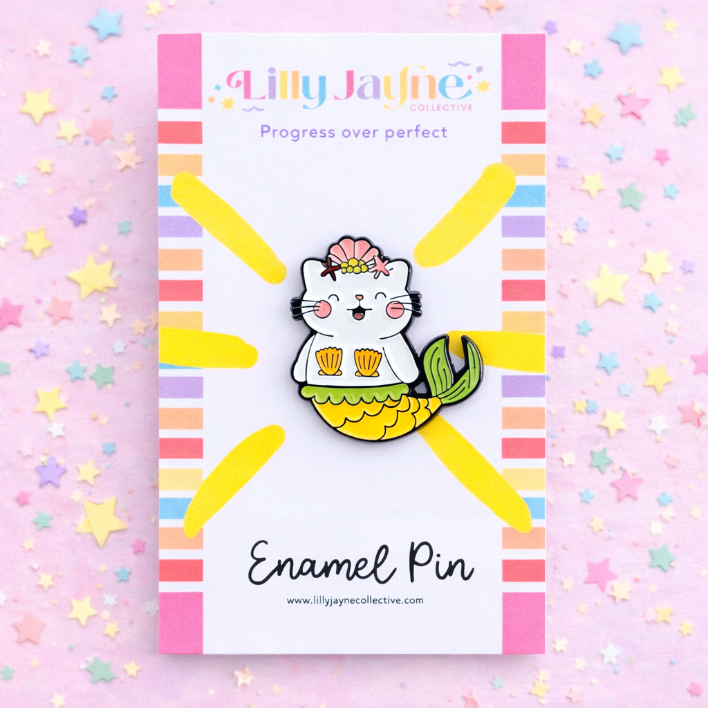 Enamel pin with a cat mermaid design on a colorful background with 'Lilly Jayne' branding.