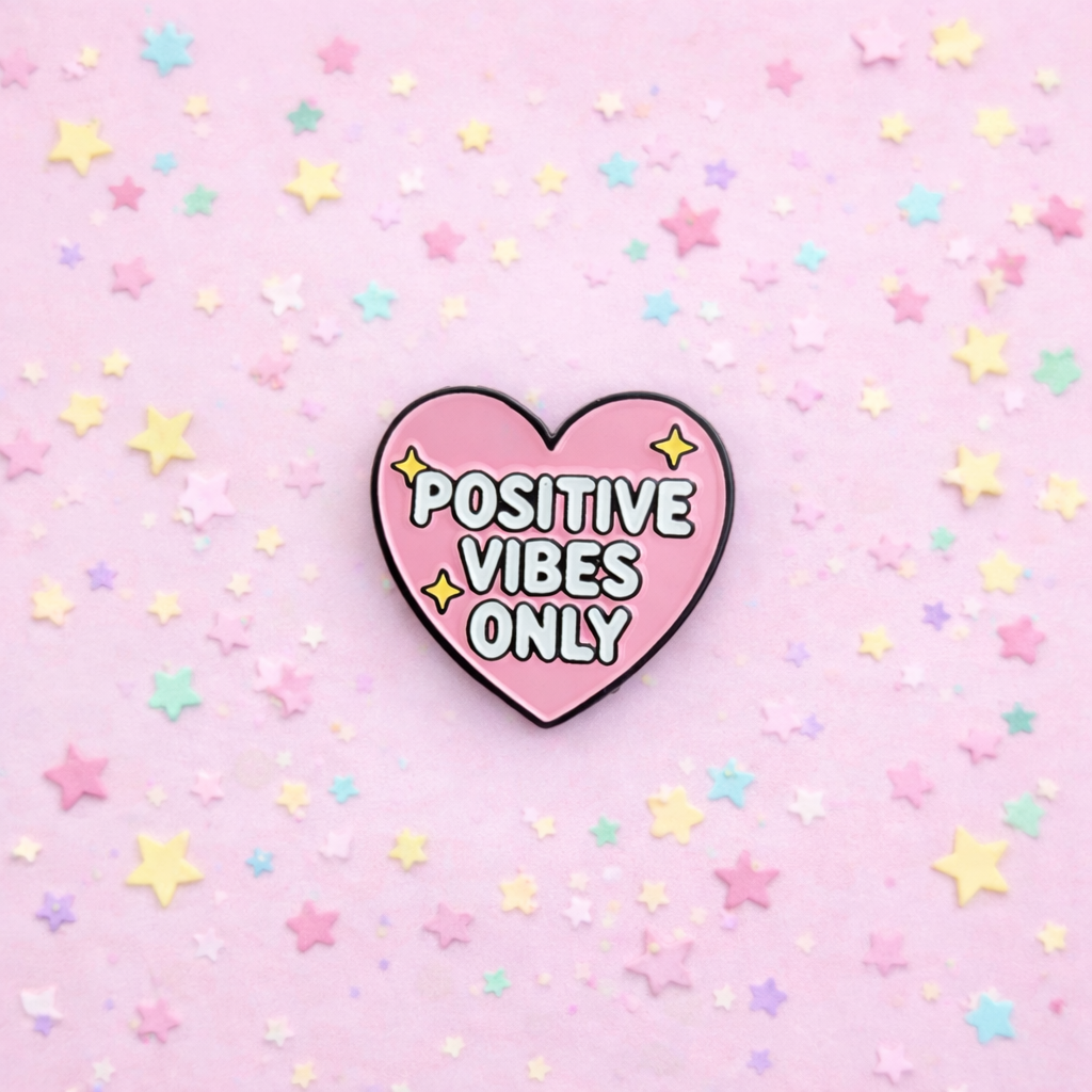 Heart-shaped 'Positive Vibes Only' pin on a pink background with stars