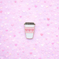 Enamel pin of a coffee cup with heart designs on a pink heart-patterned background