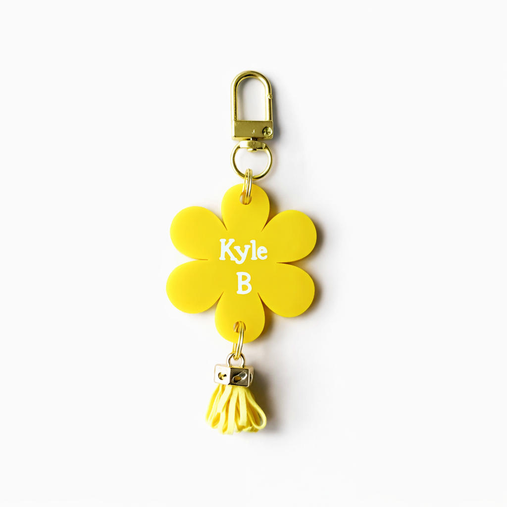 Yellow flower-shaped keychain with 'Kyle B' engraving on a white background