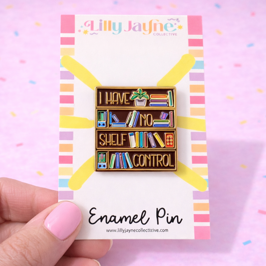 Enamel pin with bookshelf design on a colorful card held by a hand