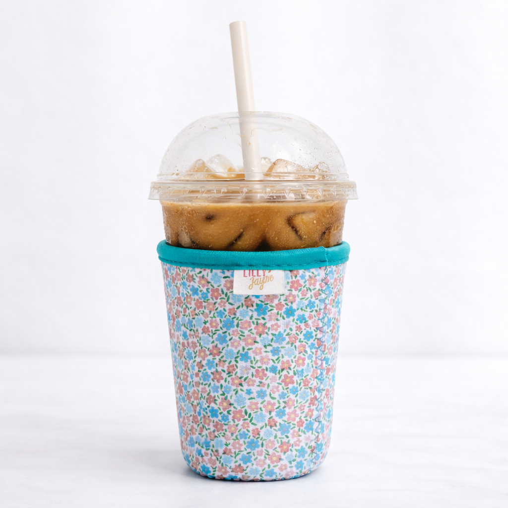 Floral-patterned cup sleeve with a plastic cup containing iced coffee on a white background