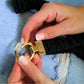 Gold belt buckle being held by a person against a denim background