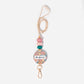 A personalized lanyard featuring a round name tag with floral patterns, attached to a metal clip and a key ring, with colorful silicone beads on the strap.