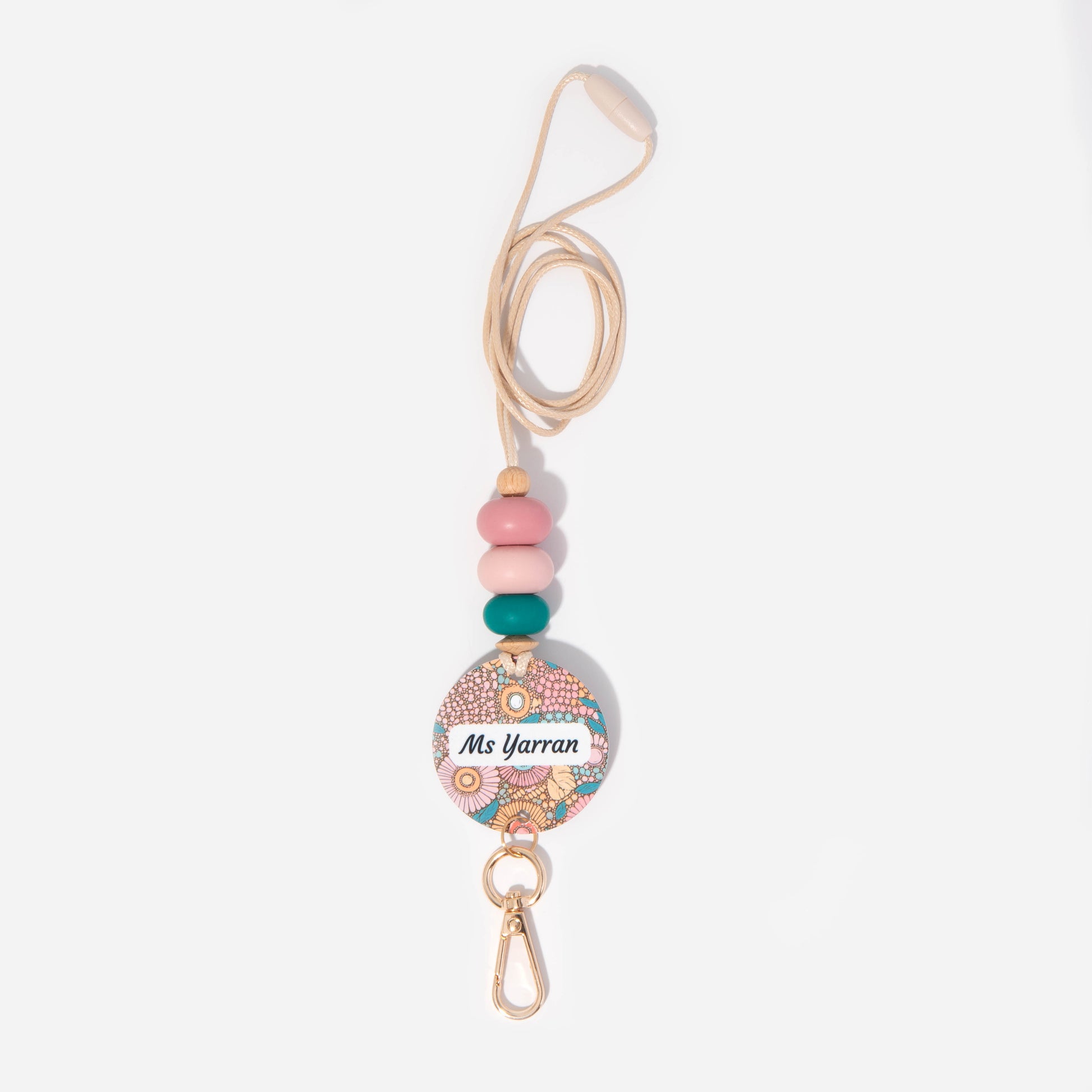 A personalized lanyard featuring a round name tag with floral patterns, attached to a metal clip and a key ring, with colorful silicone beads on the strap.