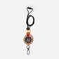 A lanyard featuring a round badge with Aboriginal art patterns, attached to a metal clip and a key ring, with silicone beads in black, red, and yellow colors along the strap.