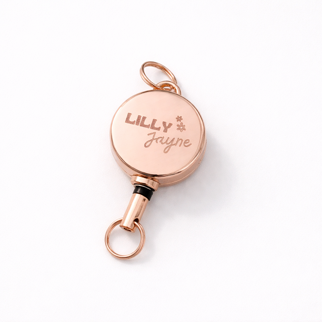 Rose gold retractable badge holder with 'LILLY Jayne' engraving on a white background