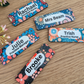 Colorful name tags with floral designs on a wooden surface
