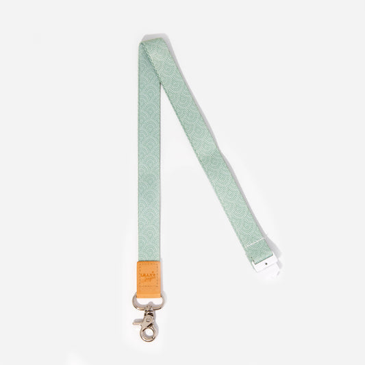 A sage green fabric lanyard with a faux leather trim and a metal clasp.