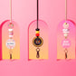 Decorative keychains hanging against a pink background